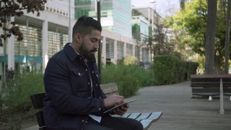 Serious-bearded-man-using-tablet-pc-outdoor